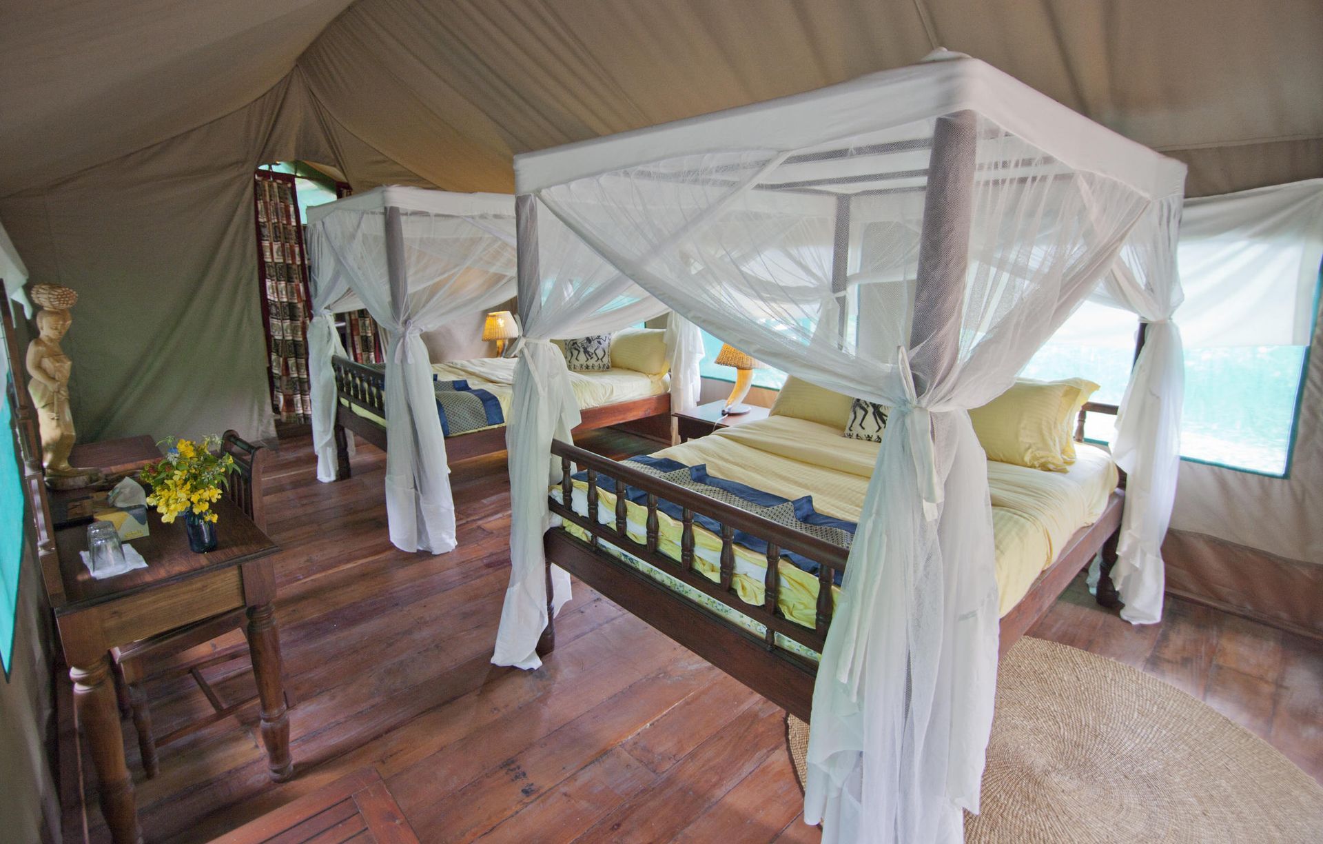 A four poster bed in a tent with mosquito nets.