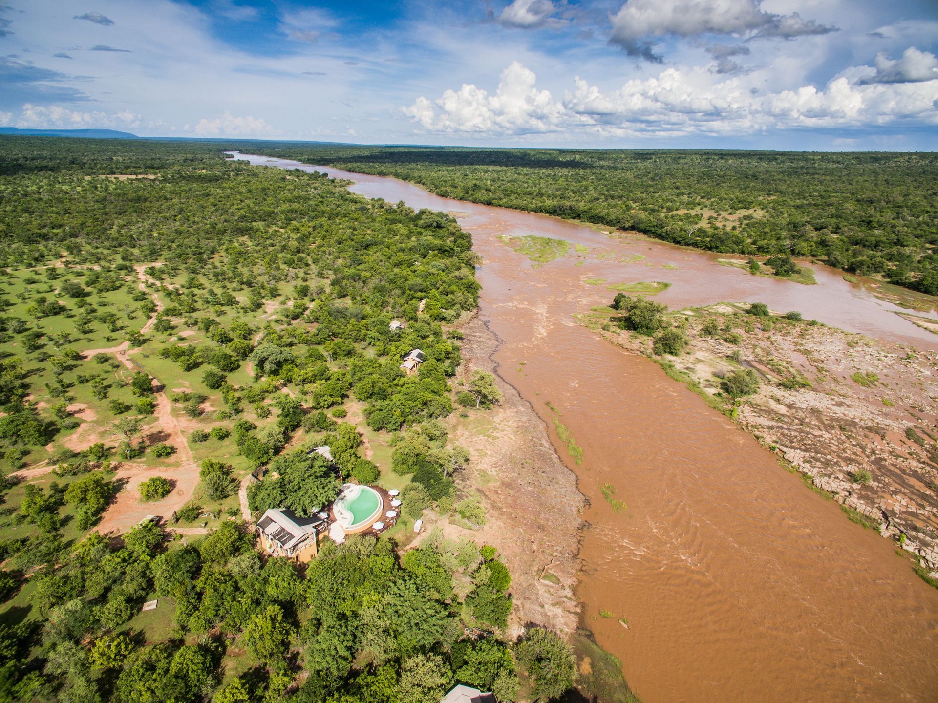 An aerial view of a river flowing through a lush green forest.