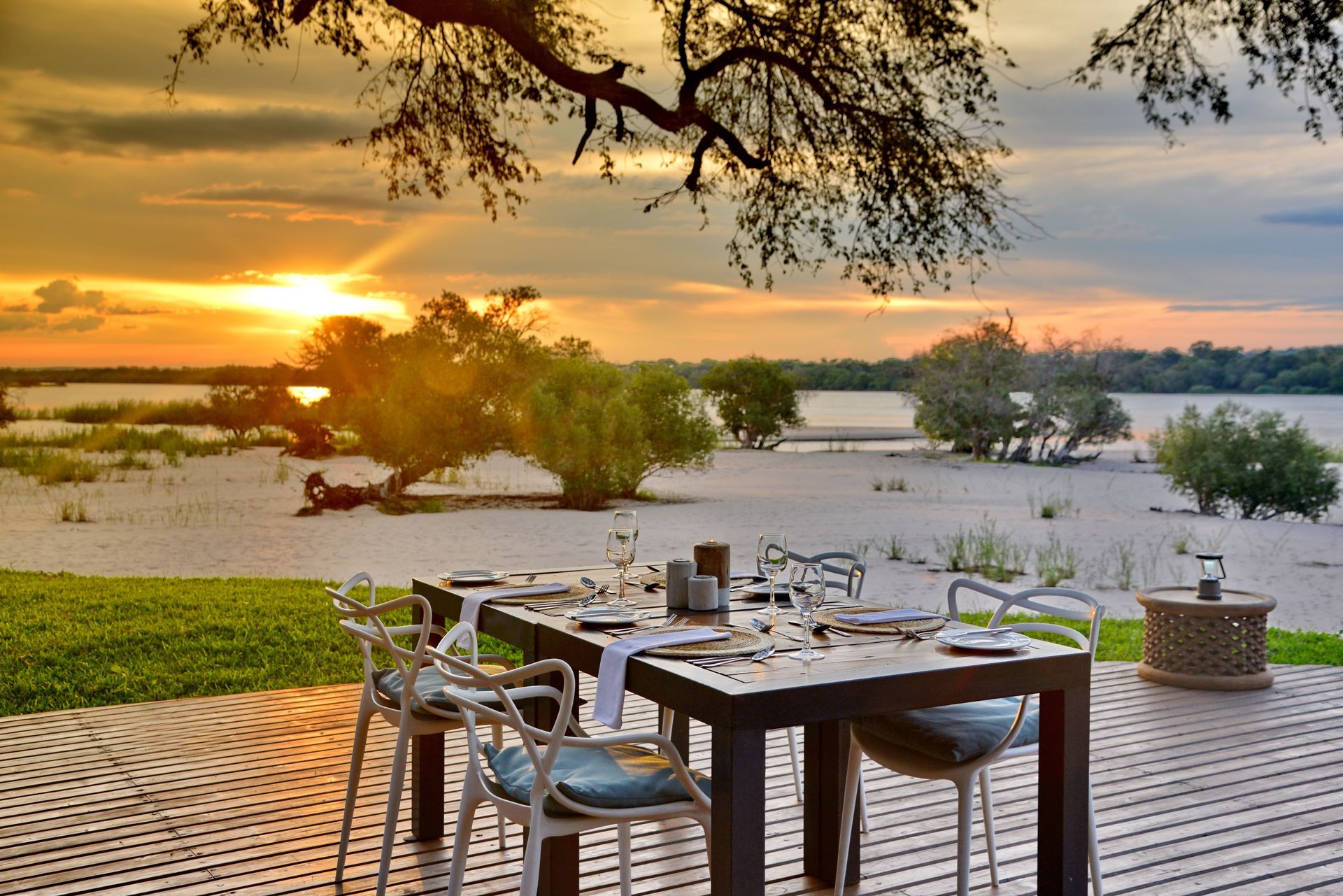 A table and chairs on a deck overlooking a body of water at sunset