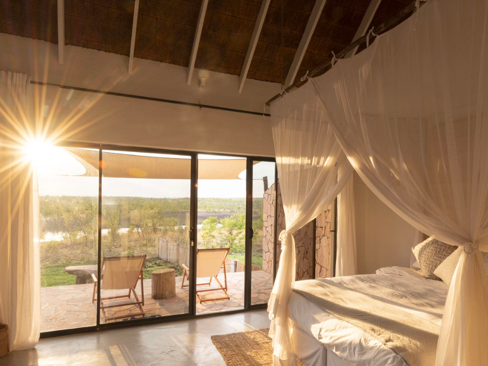 A bedroom with a canopy bed and a sliding glass door.