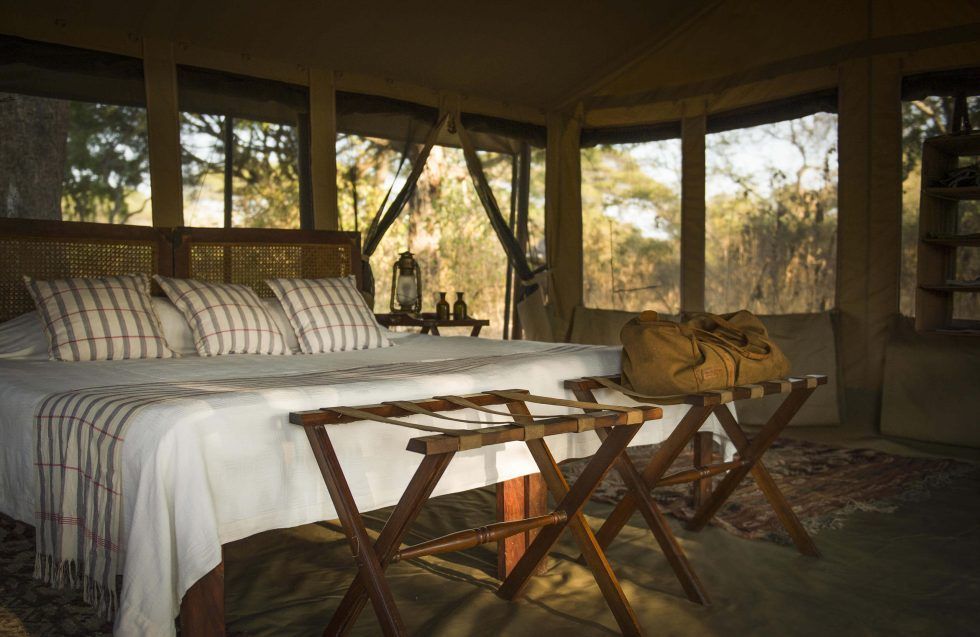 There is a large bed in the middle of the room with a lot of windows.
