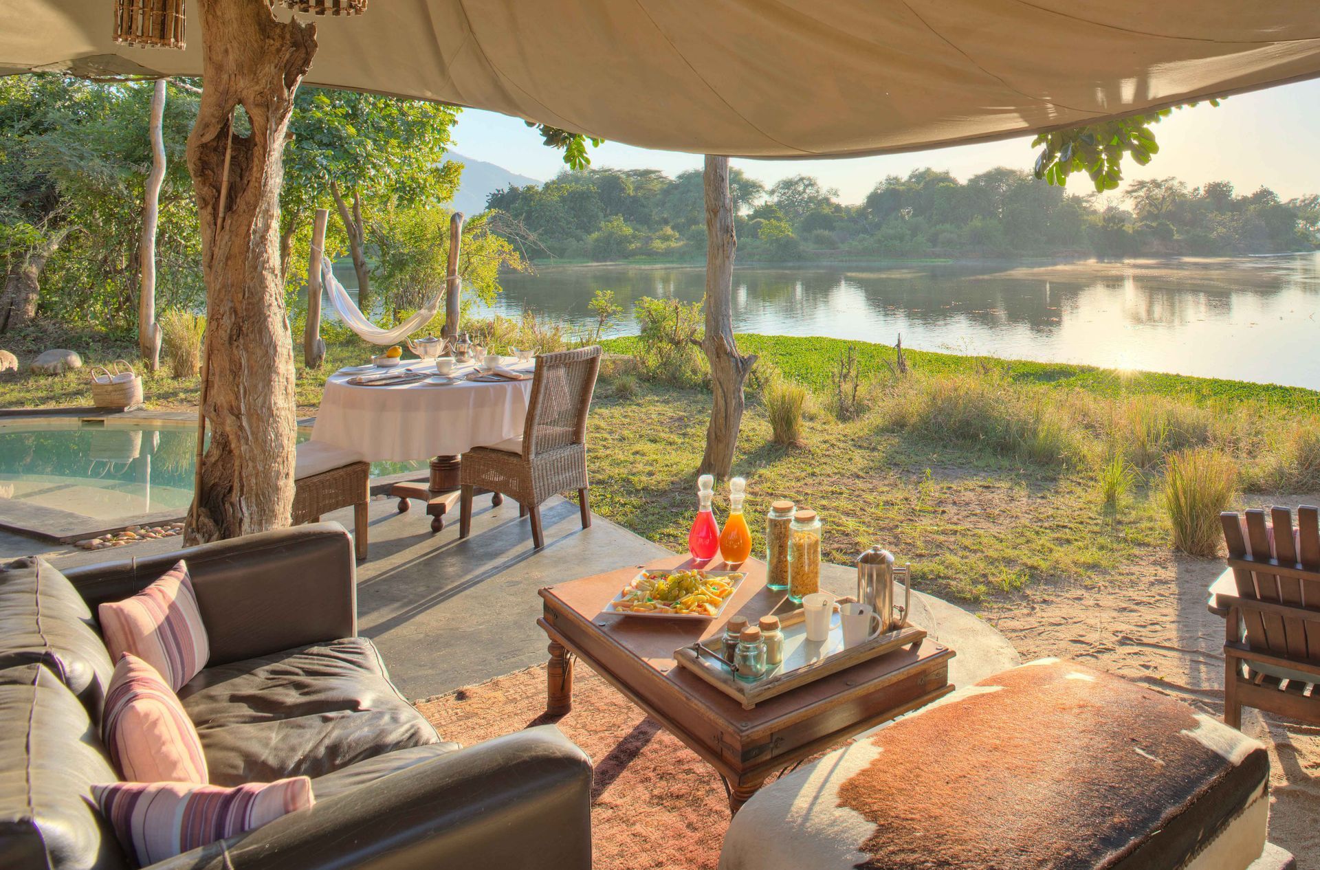A living room with a couch , chairs and a table with a view of a lake.