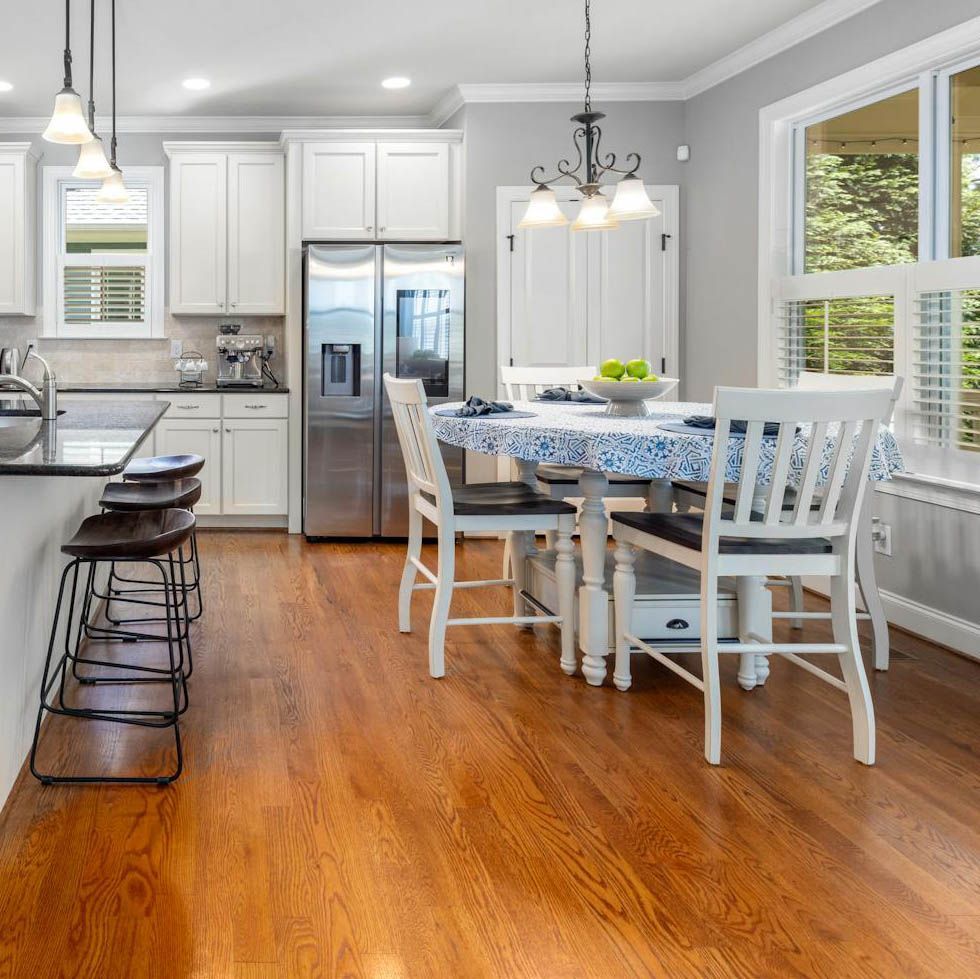 Bright kitchen with white cabinets, stainless steel appliances, and a round table with four chairs.