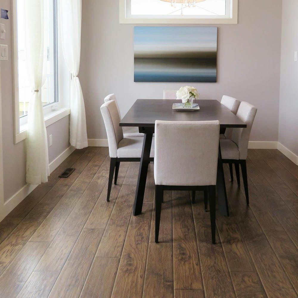 Dining room with dark wood table and chairs, hardwood floor, white curtains and abstract art.