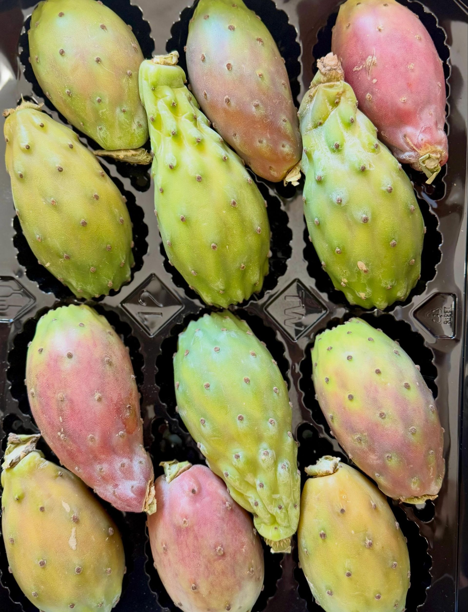 Prickly pear fruits in a carton, yellow, green, and pink