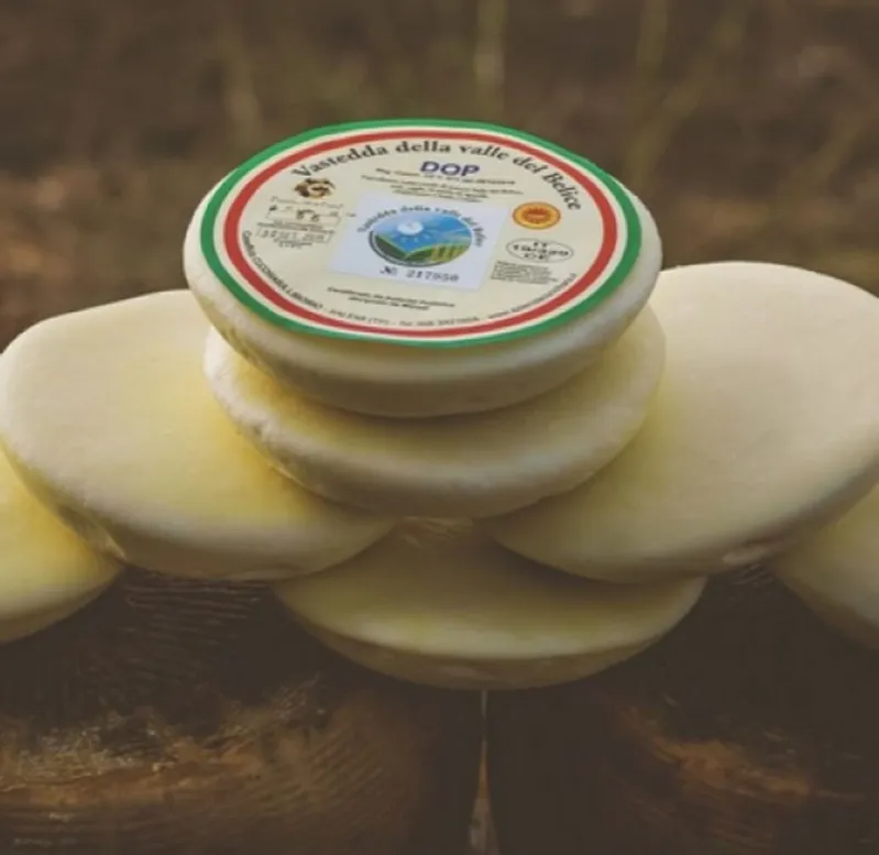 Stacked round cheese wheels with a labeled lid on top, against a blurred brown background