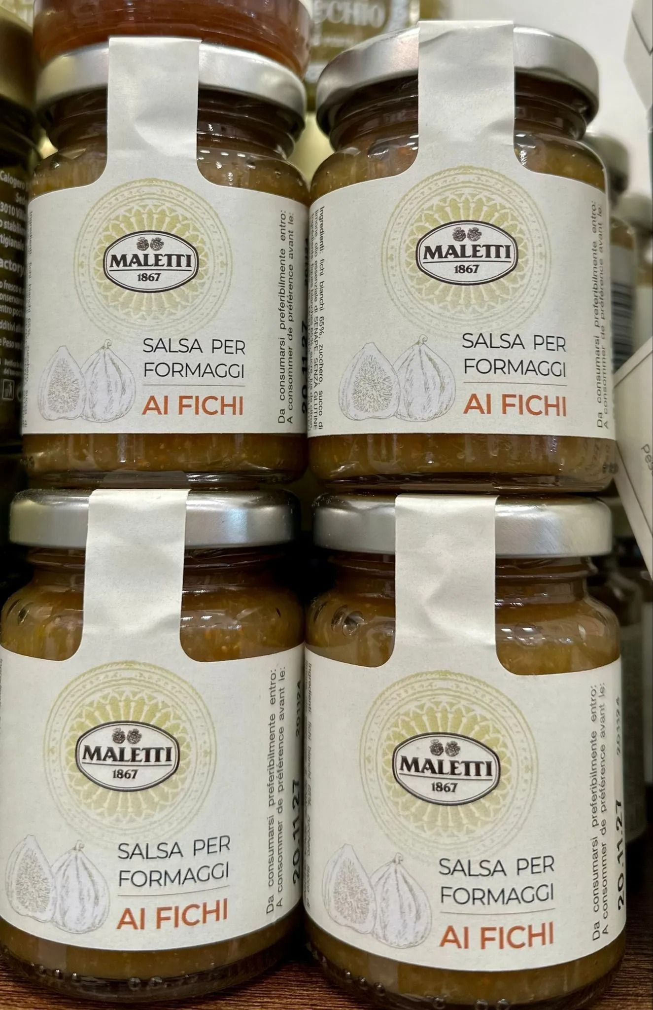 Jars of white fig jam with beige labels stacked on a shelf