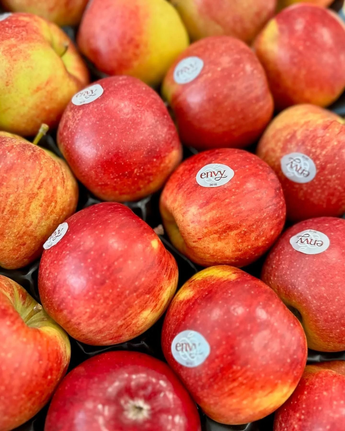 Red apples with sticker labels piled together at a market display