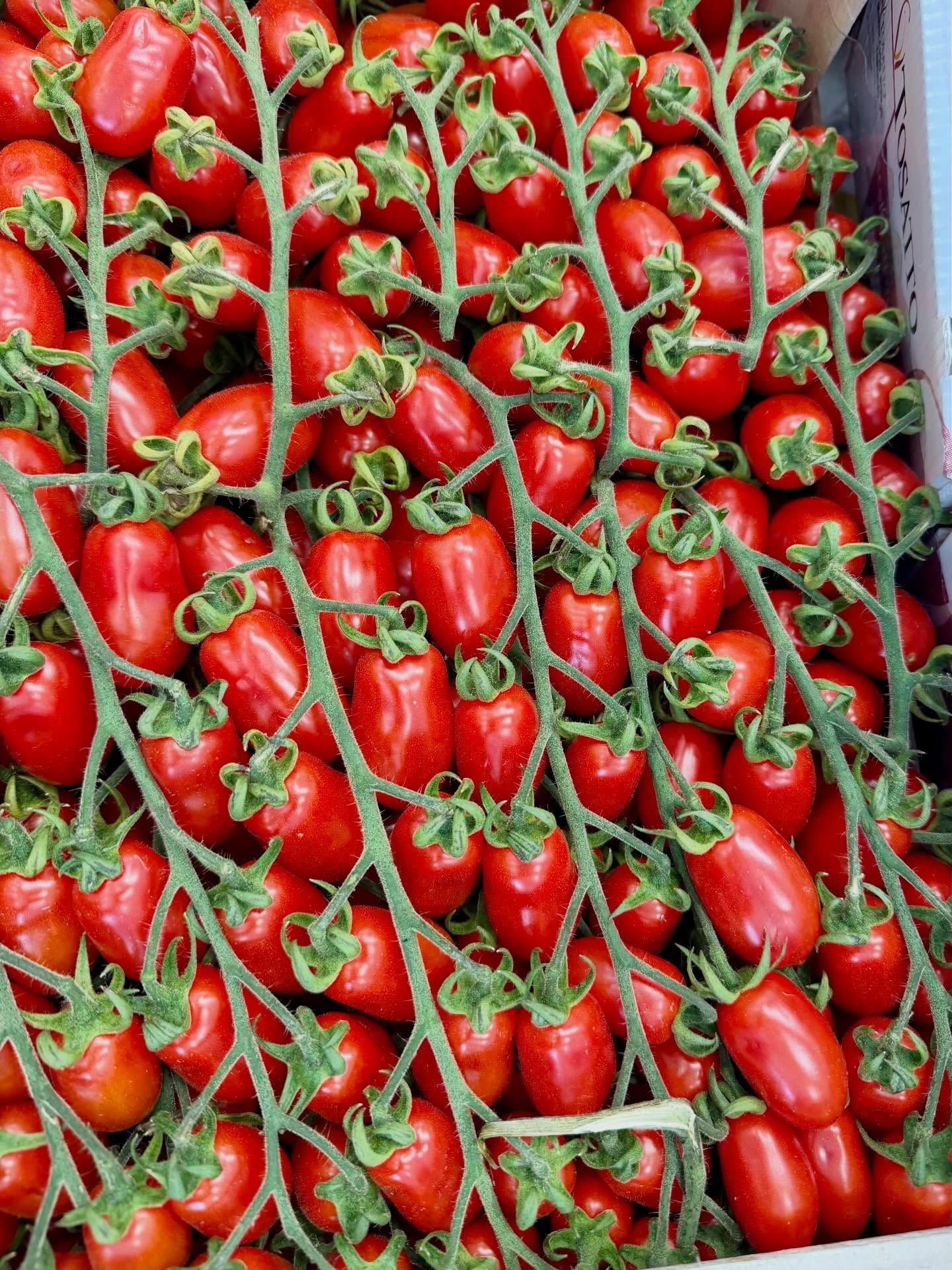 Crate filled with ripe red strawberries with green stems, stacked tightly together