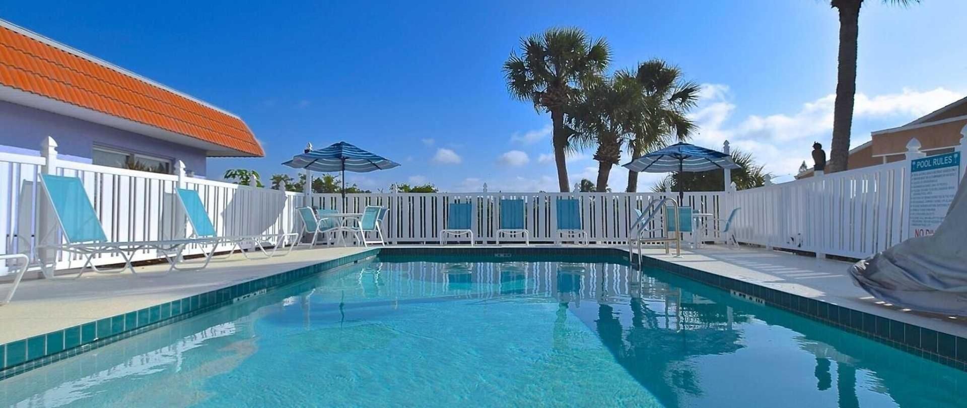 A large swimming pool surrounded by chairs and umbrellas.