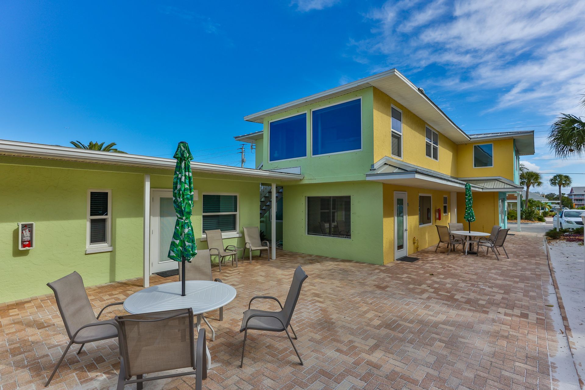 Yellow and green two-story building with outdoor seating and umbrellas under a clear blue sky.