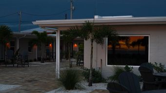 Outdoor patio at dusk with white columns, patio furniture, and warm lights under a darkening sky