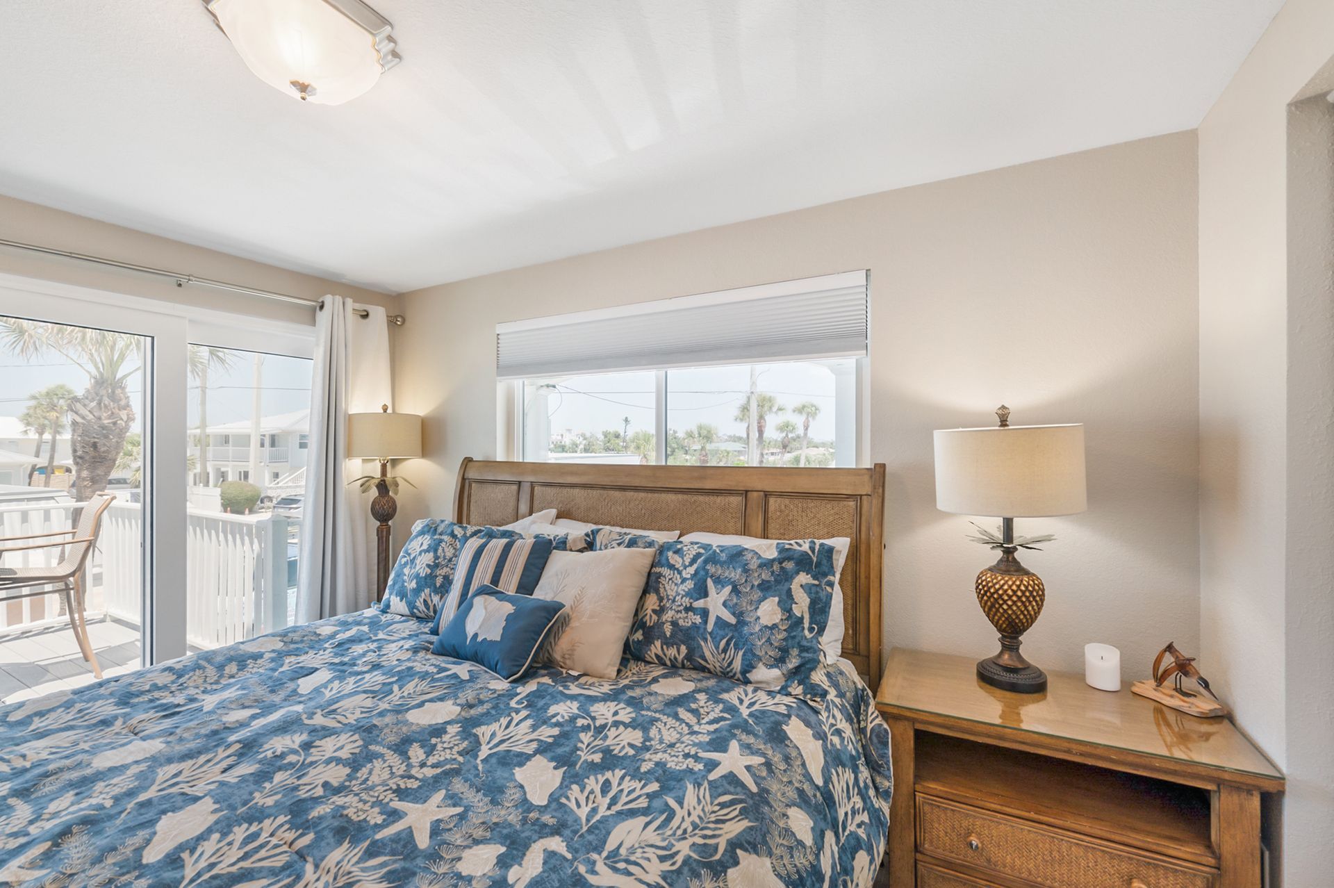 Bedroom with blue patterned bedding, a wooden headboard, and a balcony view.