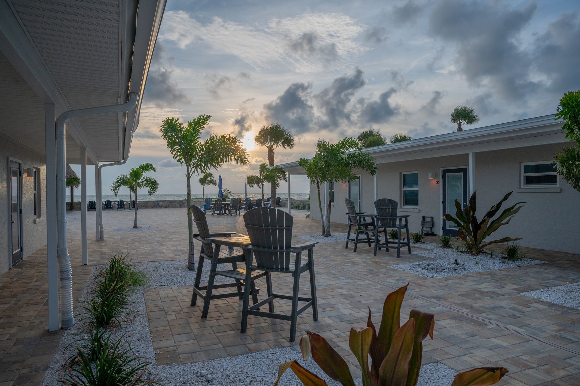 A yellow house with a patio with tables and chairs and umbrellas