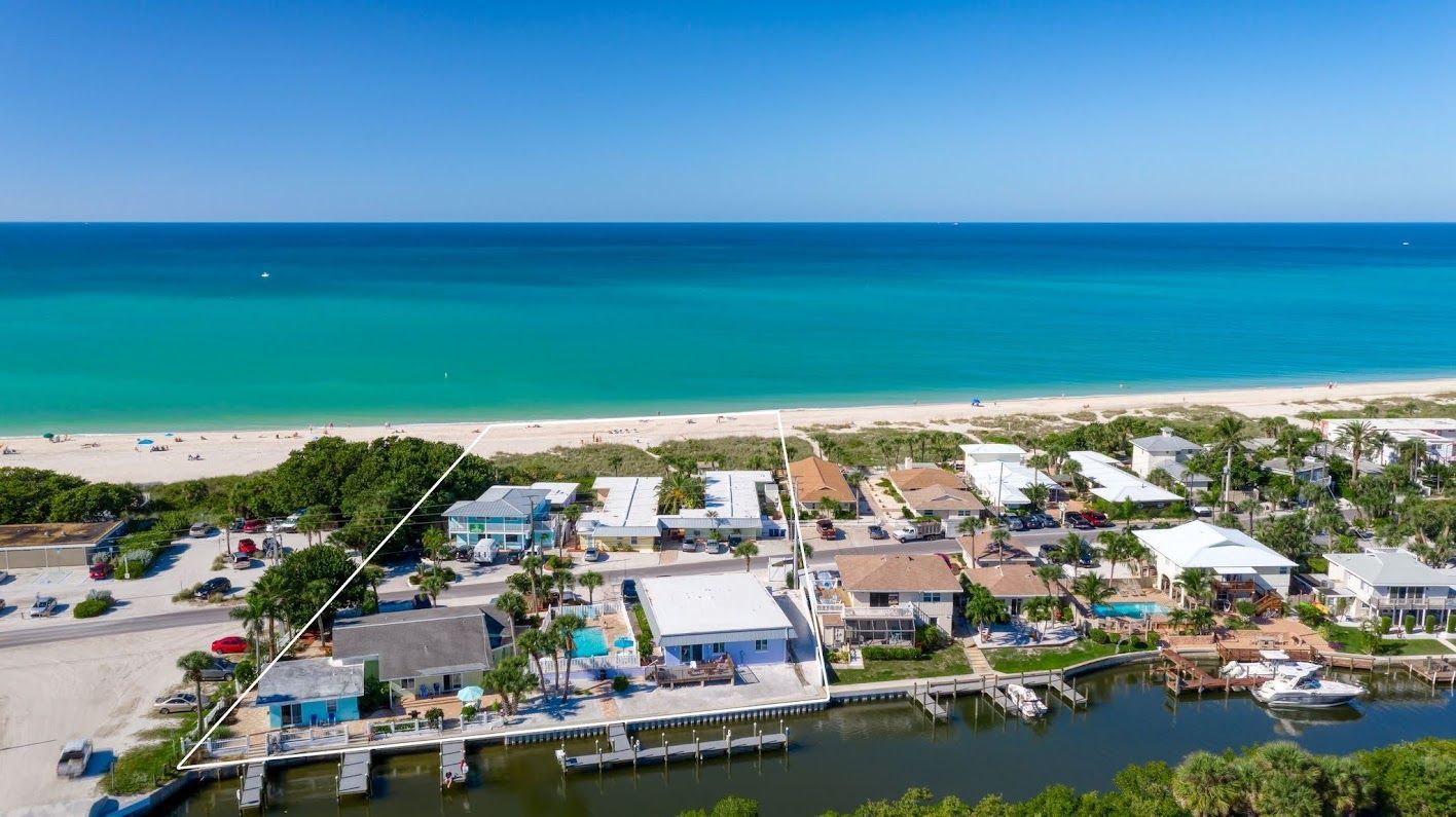 Aerial view of beachside houses, turquoise ocean, blue sky, and a waterway.
