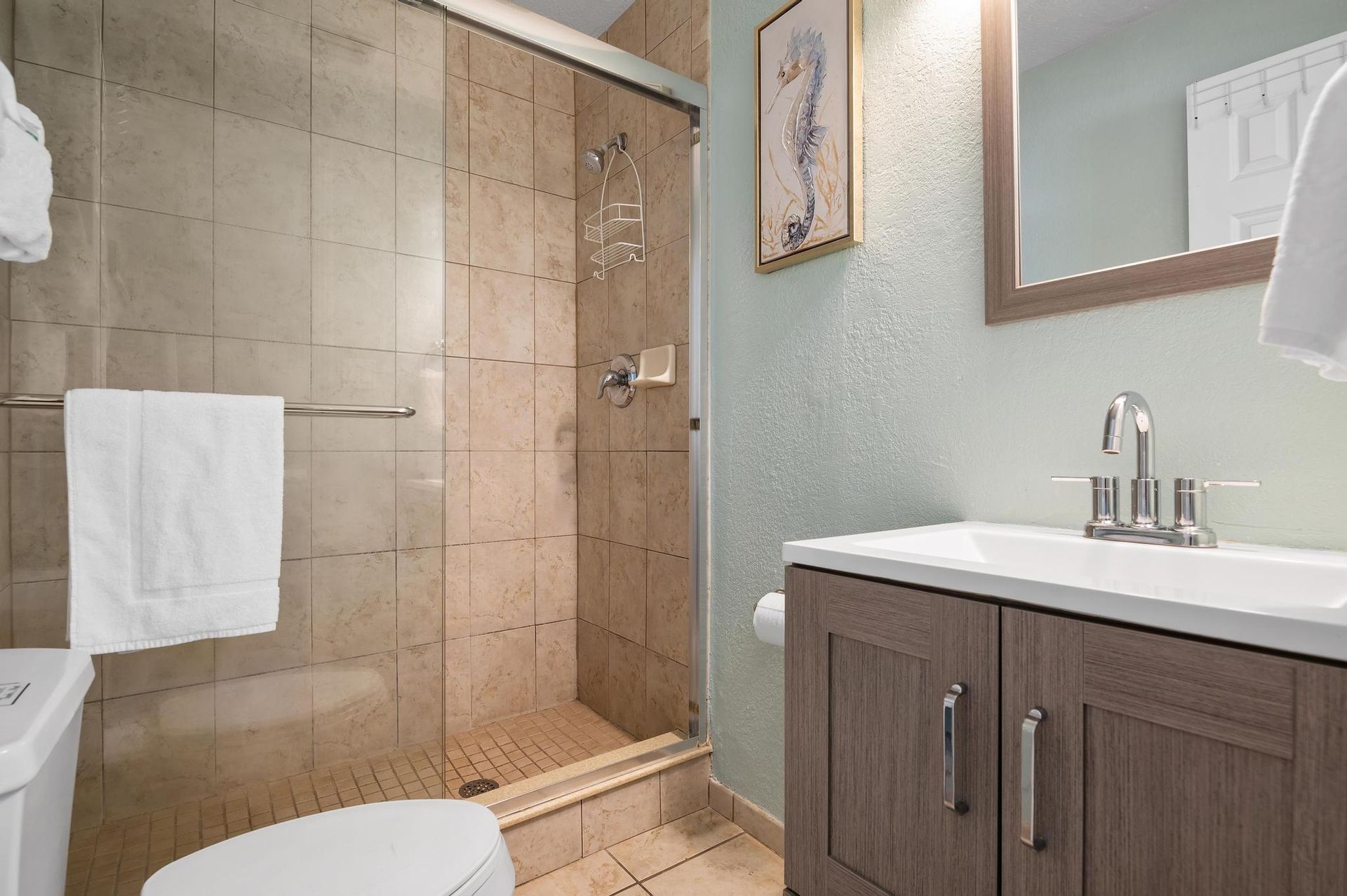 A bathroom with a toilet , sink , mirror and shower.