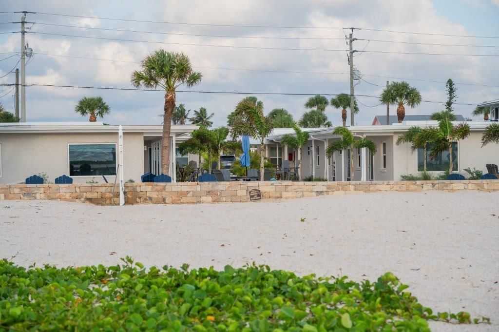 Stormy coastal view with white buildings, palm trees, and floodwater in the foreground