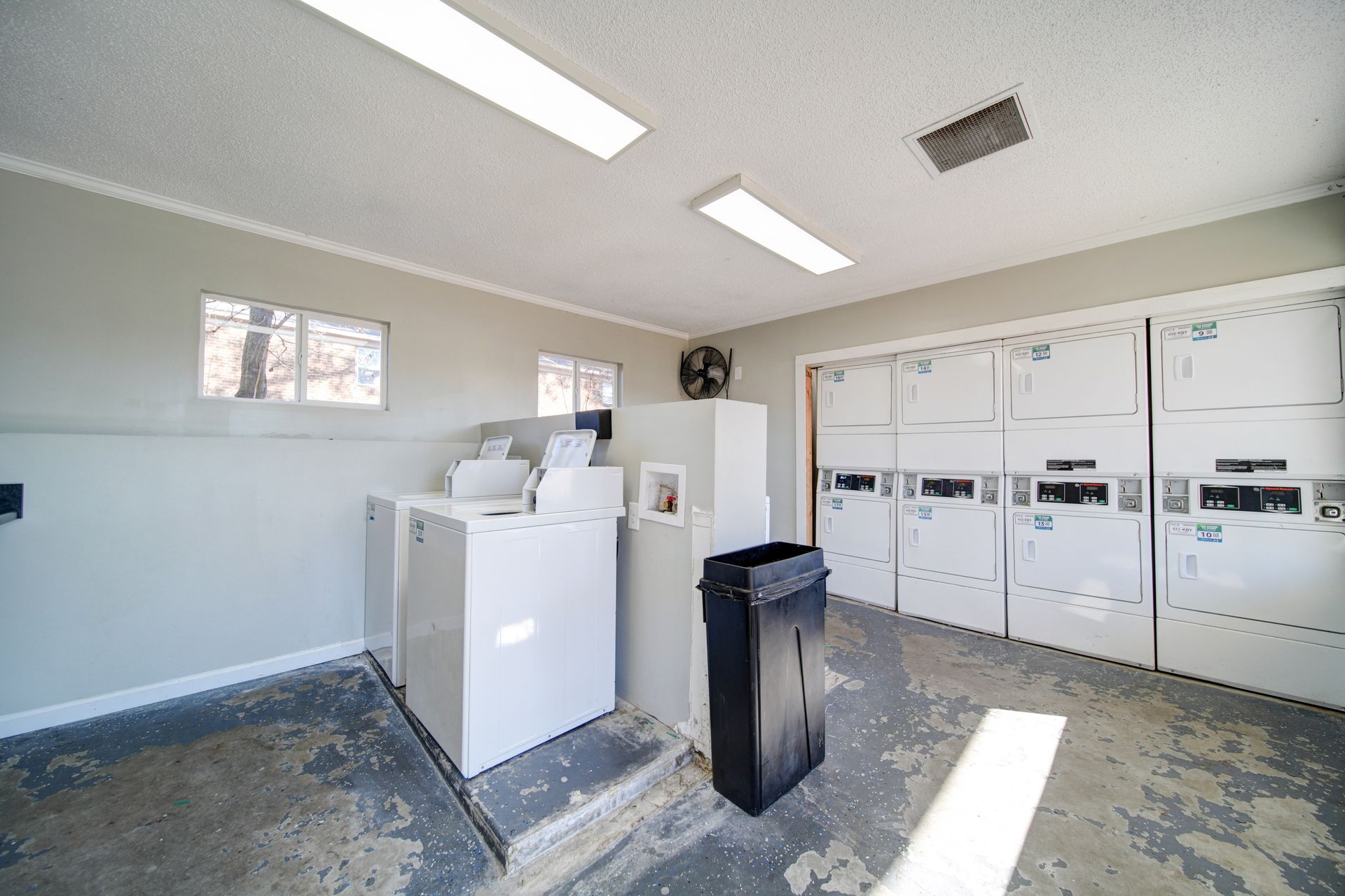 Laundry room with white appliances and cabinet-lined walls, lit by two ceiling lights.