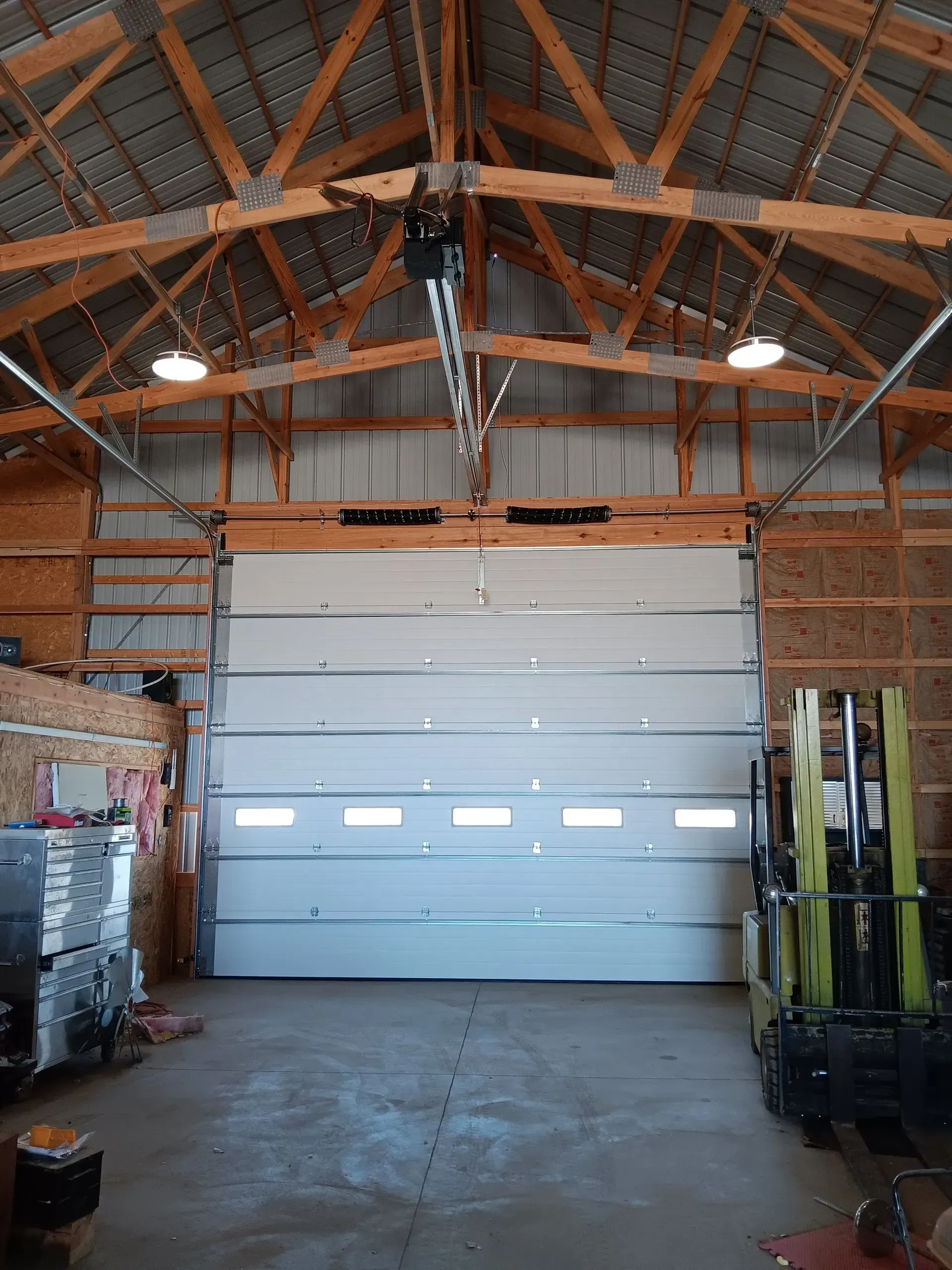 A garage with a large garage door and a forklift in it.
