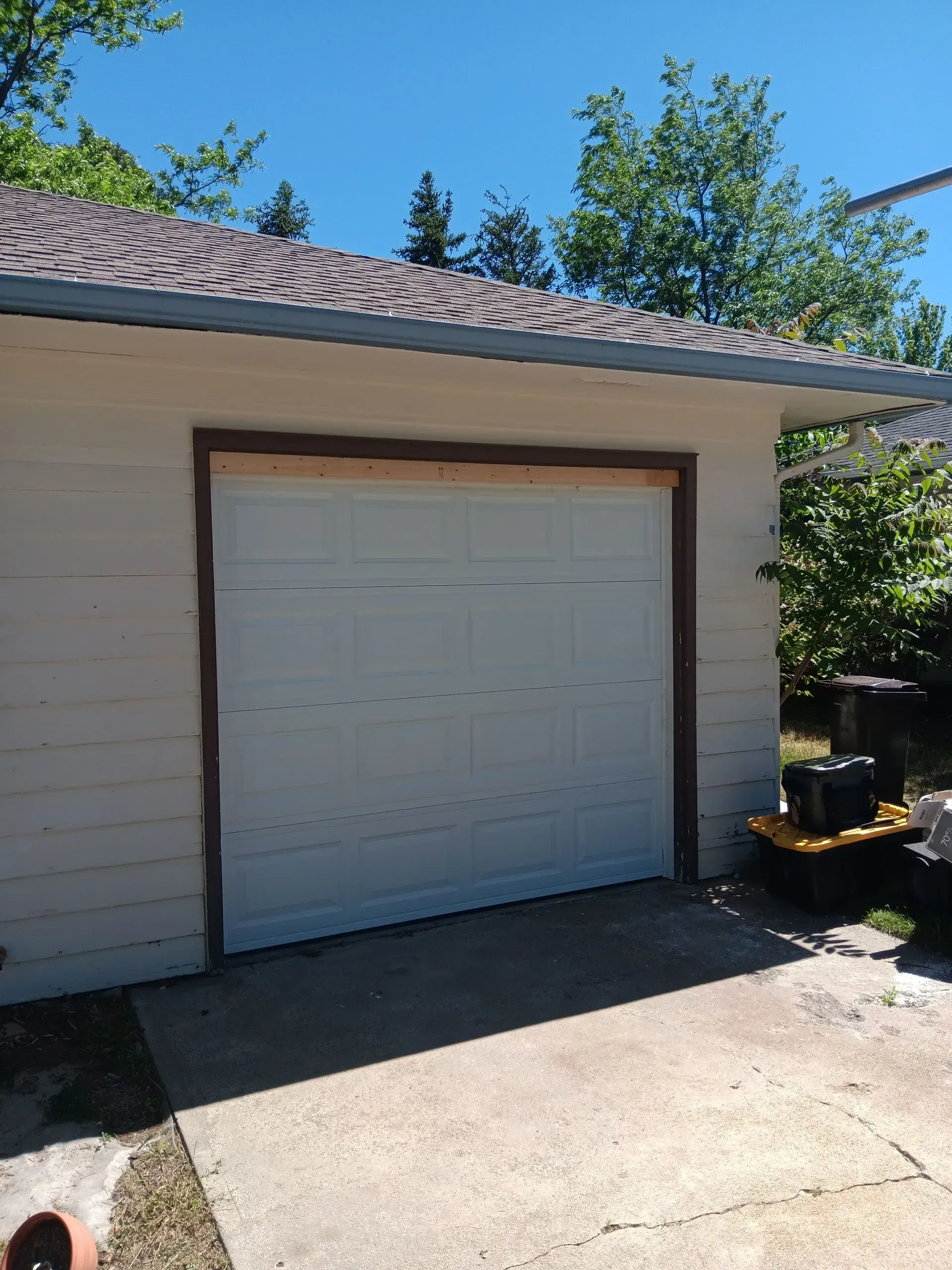 A white garage door is sitting in the driveway of a house.