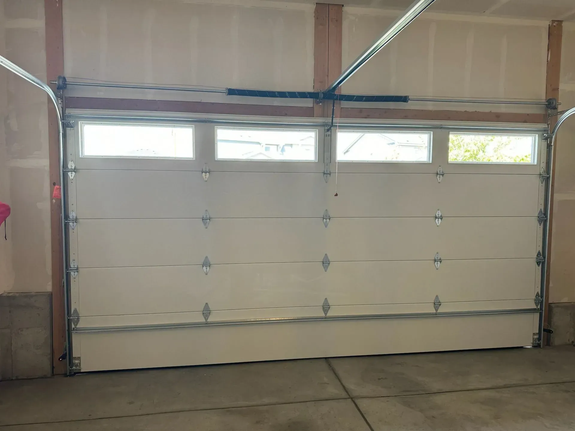 A white garage door with three windows is open in a garage.