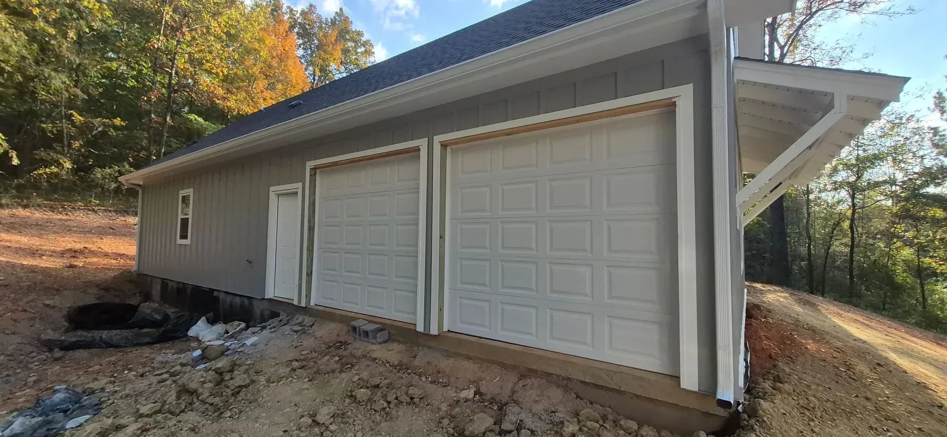 A garage with three garage doors is sitting on top of a dirt hill.