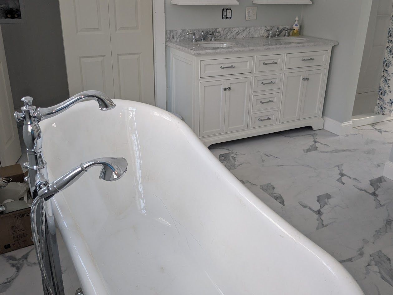 Bathroom under renovation with exposed floor, tools, and a toilet against white tiled walls
