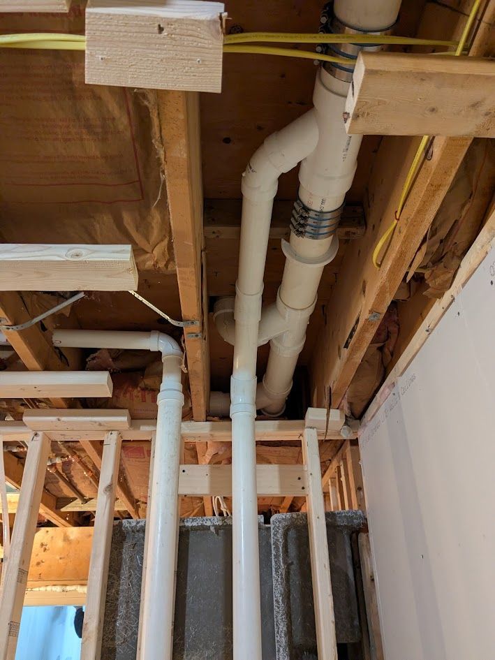 Exposed ceiling pipes and wooden framing in an unfinished interior wall cavity.