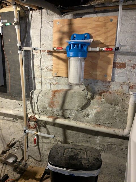 Compact water filtration system on a table beside a faucet and lab water cartridges