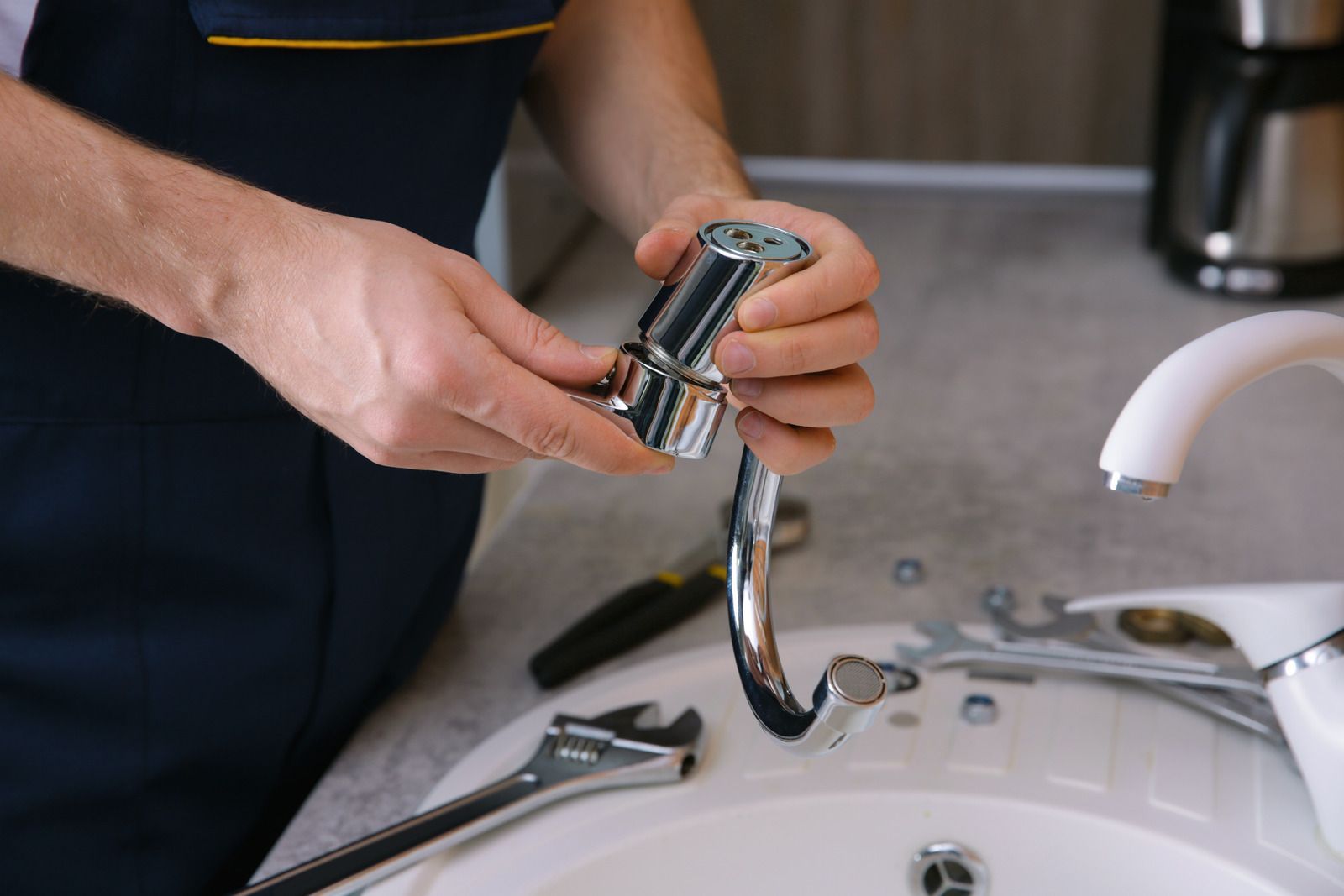 Person attaching a chrome faucet sprayer in a bathroom sink.