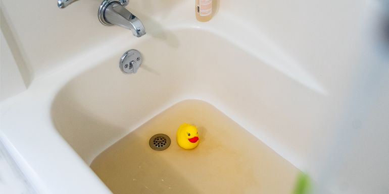 A bathtub with a yellow rubber duck in it.