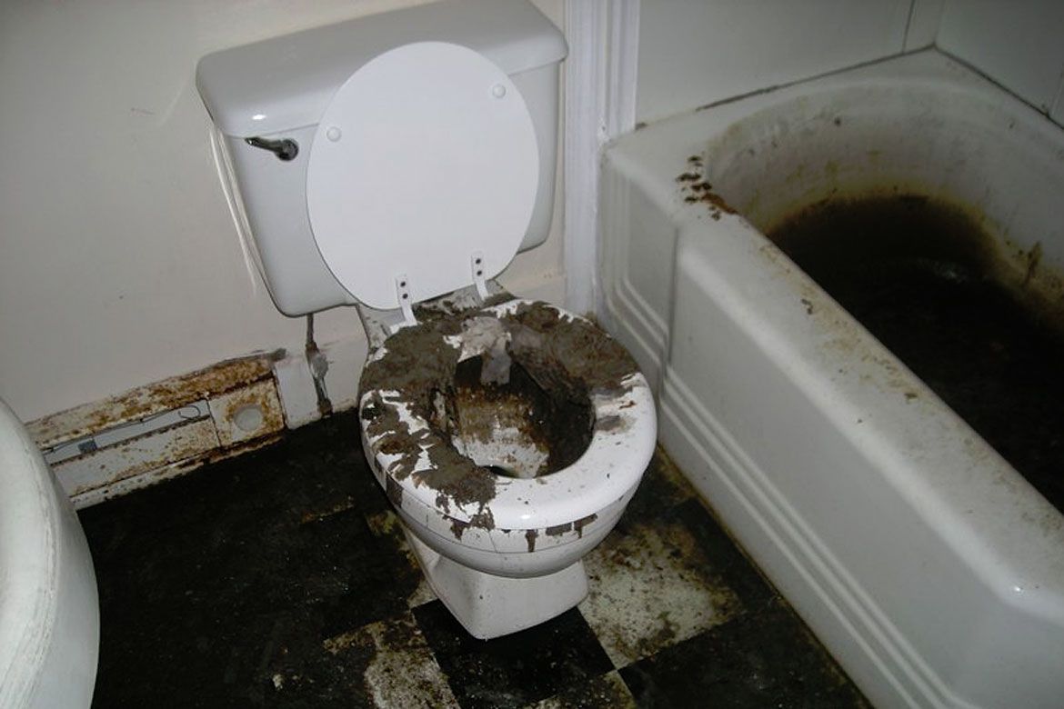 A dirty toilet in a bathroom next to a bathtub
