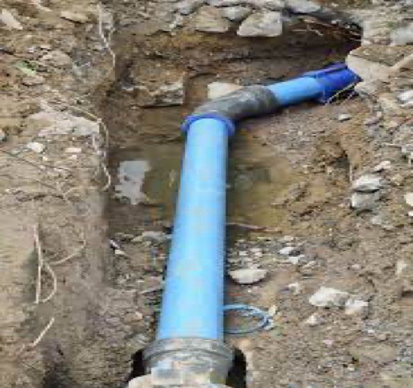 A sewer line pipe is being installed in a hole in the ground.