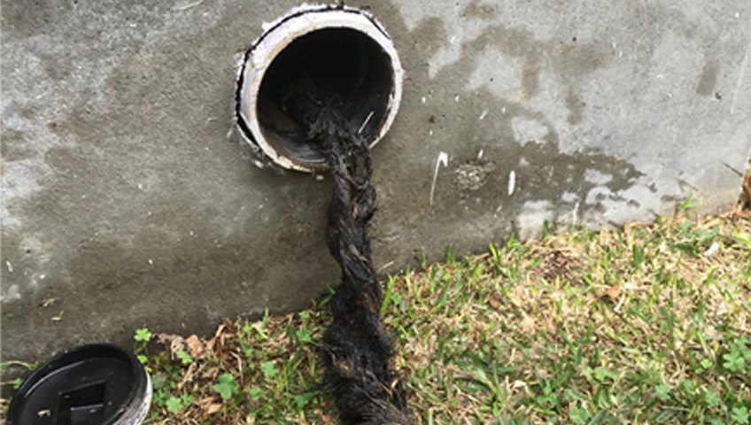 A drain pipe with a lot of dirty water coming out of it.