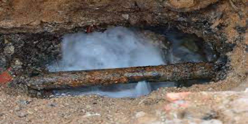 A rusty pipe is coming out of a hole in the ground.