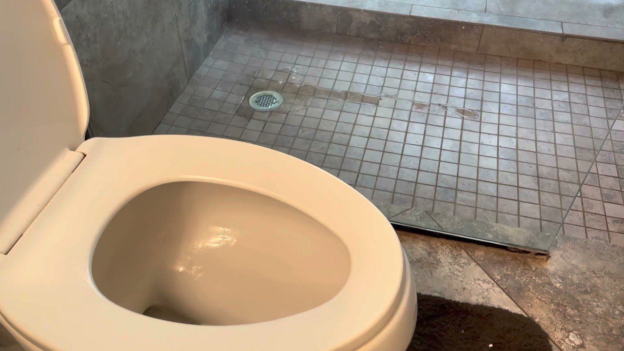 A toilet is sitting in a bathroom next to a shower.