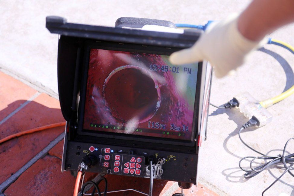 A person is pointing at a screen with a picture of a pipe on it.