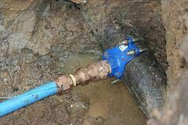 A blue pipe is connected to a black pipe in the dirt.