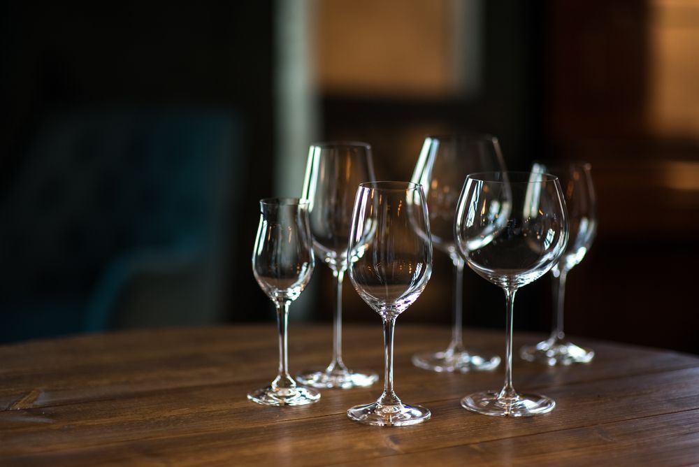 A group of wine glasses sitting on top of a wooden table.