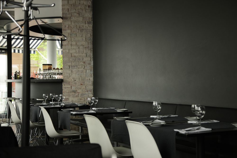 A restaurant with tables and chairs and a brick wall.