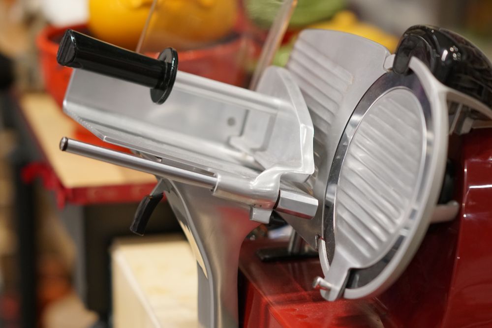 A meat slicer is sitting on top of a wooden table.