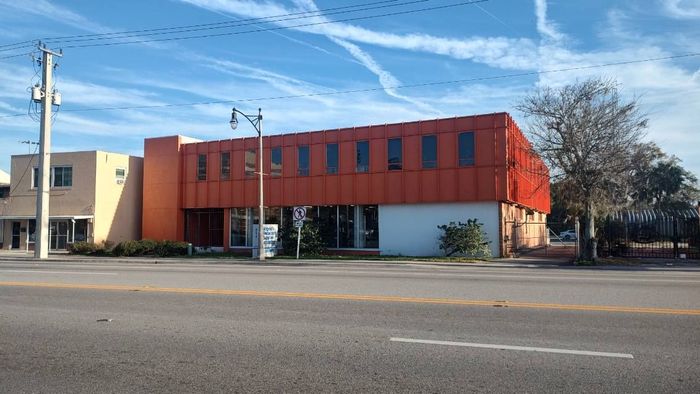 A large orange building is sitting on the corner of a street.