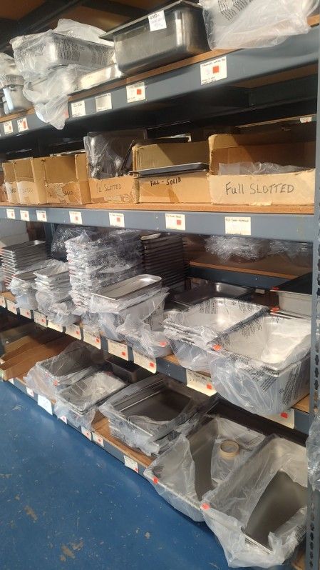 A warehouse filled with lots of stainless steel pans and containers.