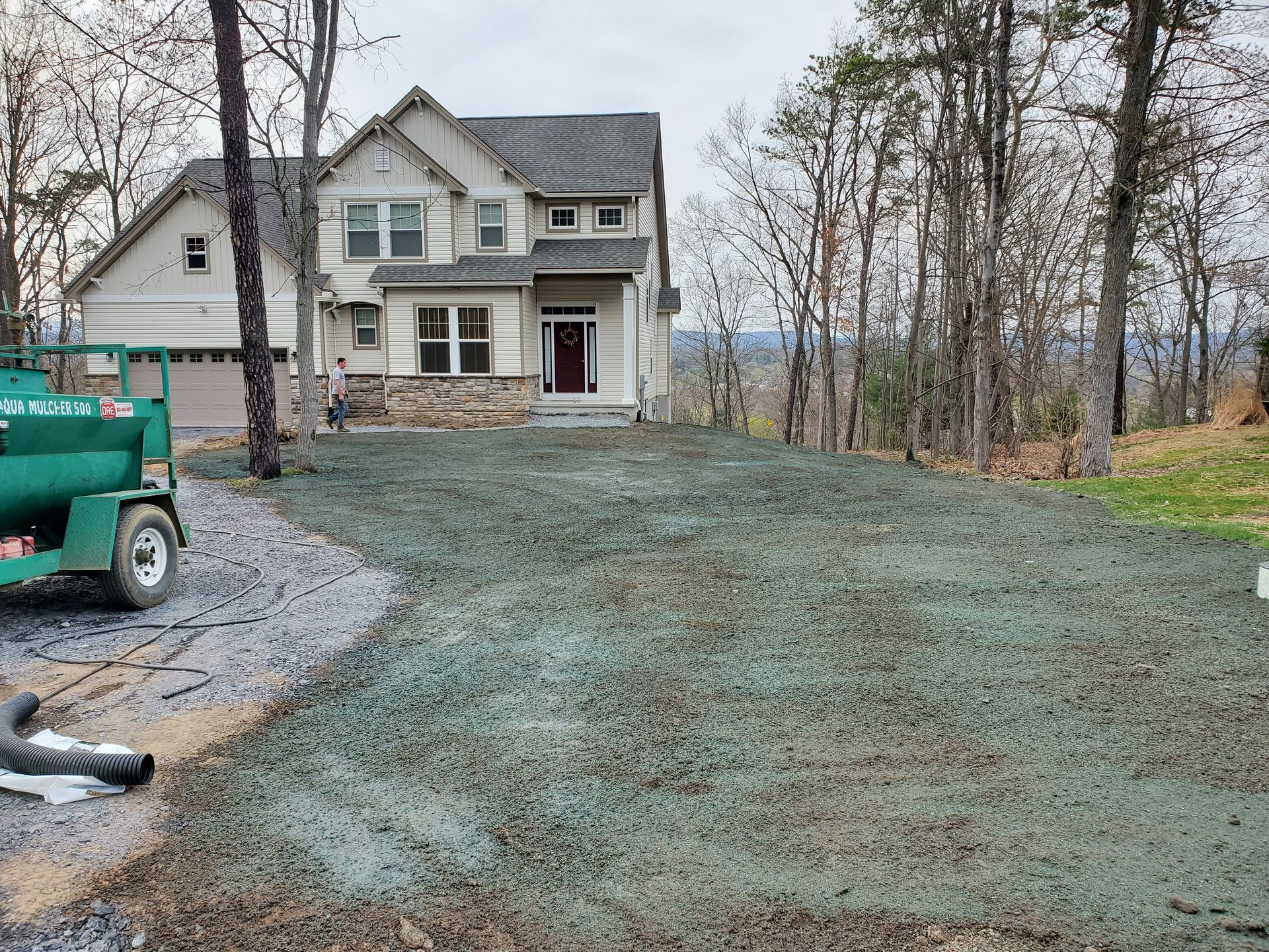 A green truck is parked in front of a large house.