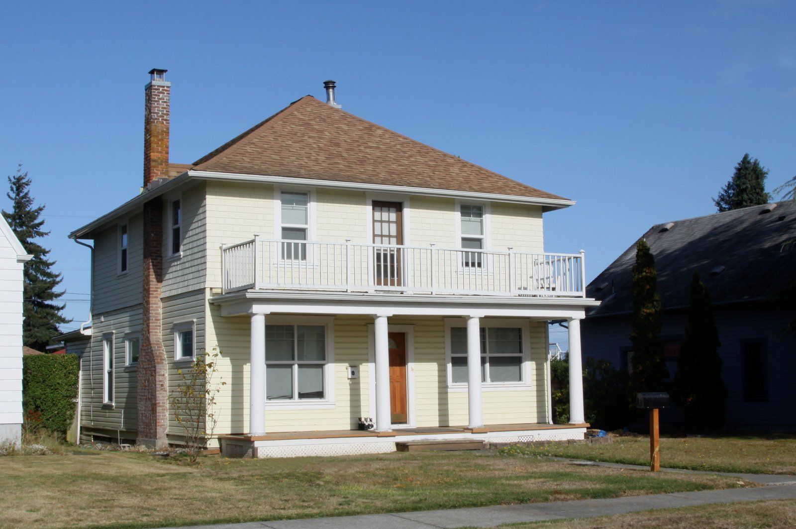 A beige retractable awning extended from a white-sided house with black trim.