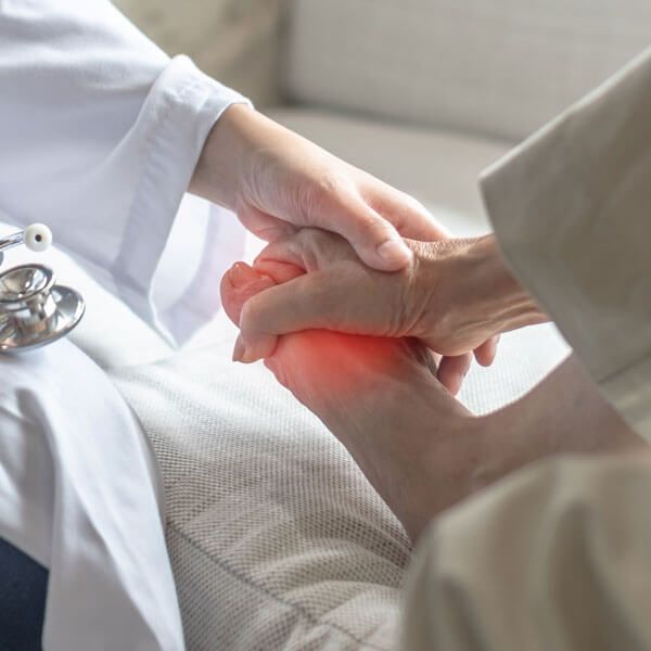 Medical professional holding a person's foot with a red, painful area near the toes