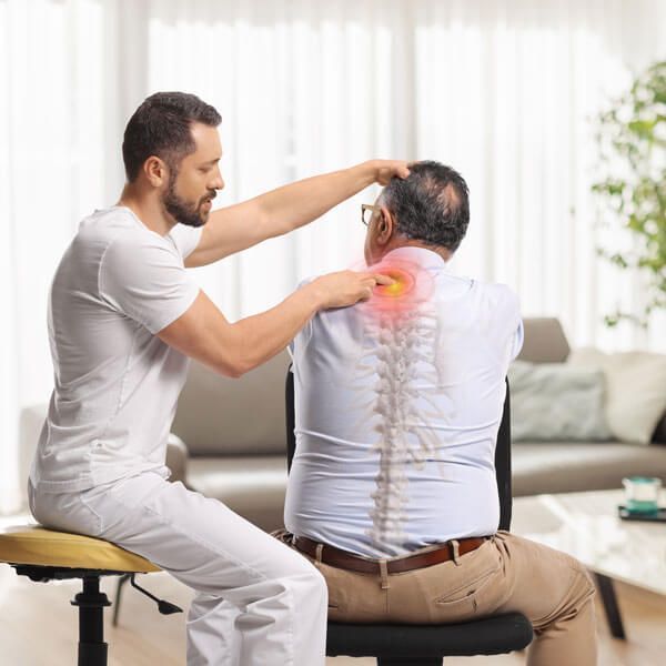 Chiropractor examining a seated patient’s neck and spine in a bright clinic room