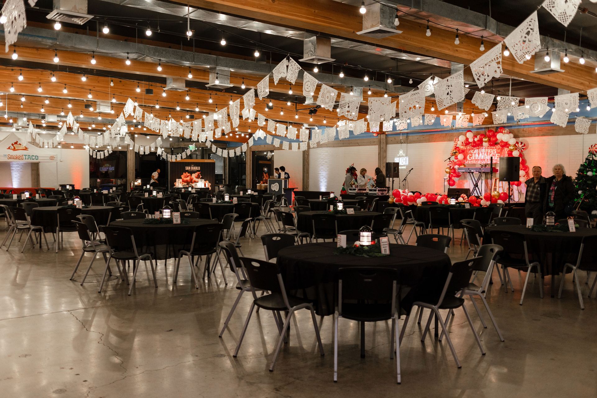 A large room with tables and chairs set up for a wedding reception.