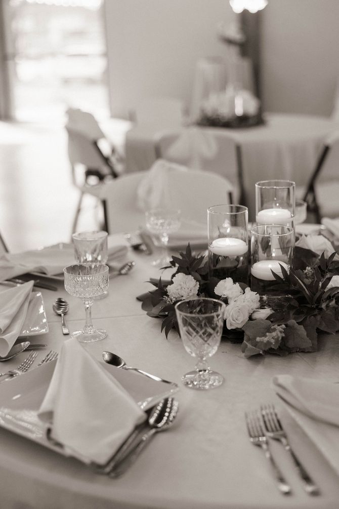 A table set for a wedding reception with plates , glasses , and flowers.