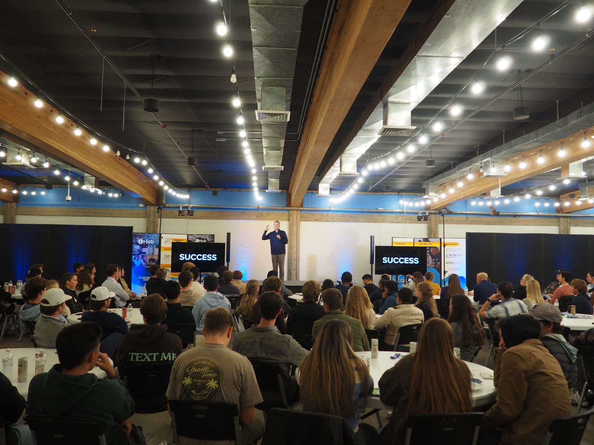 A man is giving a presentation to a large group of people in a large room.